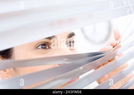 Frau guckt durch das Fenster Stockfoto