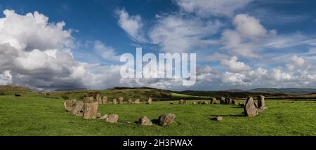 Swinside, alias Sunkenkirk Steinkreis, sonnendurchflutet mit breitem blauen Himmel und weißen Wolken; sonnendurchflutete und schattige Hügel im Hintergrund; Rinder auf dem Feld in der Nähe von Steinen. Stockfoto