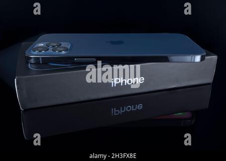 Galati, Rumänien - 14. Oktober 2021: Studioaufnahme des neuen Apple iPhone 12 Pro Max in blauer Farbe über der iPhone-Box. Isolieren auf schwarzem Hintergrund. Illustrative e Stockfoto