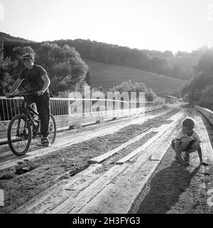 31. Juli, Russland. Altay, ländliche Szene mit spielenden Jungen und Jungen auf dem Fahrrad auf der Brücke Stockfoto