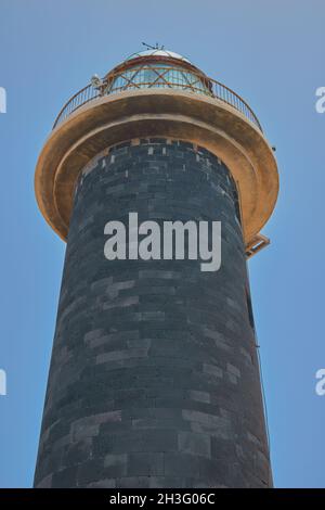 Blick auf den Leuchtturm Punta de Jandia von unten mit dunklem Ziegelturm und Glaskuppel und blauem Himmel im Hintergrund auf Fuerteventura, Kanarische Inseln, Spanien Stockfoto