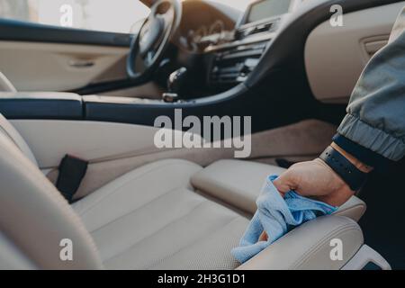 Mann, der den Innenraum des Autos mit einem Mikrofasertuch beim Autowaschservice reinigt Stockfoto