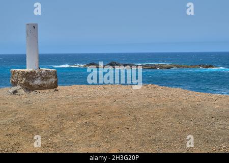 Schöne Aussicht auf das blaue Meer mit Wellen und einer kleinen Insel aus Steinen aus einer Schlucht und im Hintergrund der Horizont in Punta de Jandia, Fuert Stockfoto