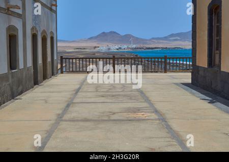 Blick auf ein Fischerdorf mit weißen Häusern am Ufer des Strandes und der Windmühle und einem Berg im Hintergrund in Puerto de la Cruz, Punta Jandi Stockfoto