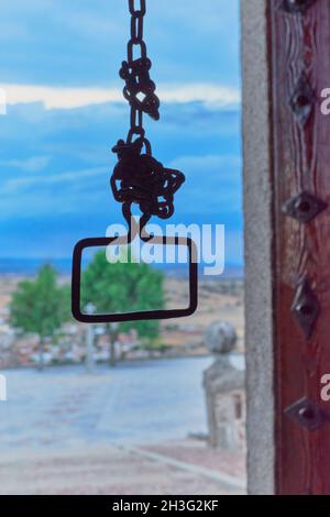 Seltsames Bild einer rostigen Kette, die vom Kirchturm aus von der Tür aus gesehen wird und vor dem Hintergrund des bewölkten Himmels bei Sonnenuntergang in Las Ventas CO Stockfoto