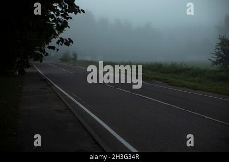 Die Straße liegt im Nebel. Autobahn ohne Autos. Landstraße am Morgen. Stockfoto