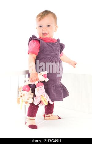 Baby Mädchen auf der Krippe stehen Stockfoto