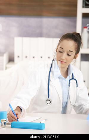 Junge Ärztin, die am Schreibtisch arbeitet Stockfoto