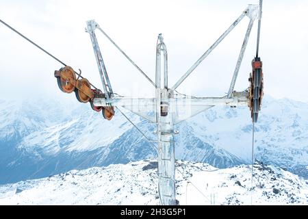 Nahaufnahme der Metallstruktur der Seilbahn auf dem Hintergrund verschneiter Berge. Skigebiet. Sessellift für Touristen, Snowboarder und Skifahrer Stockfoto