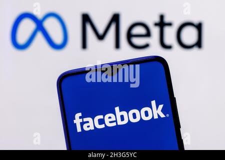 Facebook ändert seinen Namen in Meta. Smartphone mit Facebook-Logo auf dem Hintergrund des Meta-Logos. Stockfoto