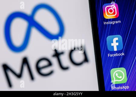 Facebook ändert seinen Namen in Meta. Smartphone mit Facebook, Whatsapp und Instagram App-Icon auf dem Hintergrund des Meta-Logos. Stockfoto