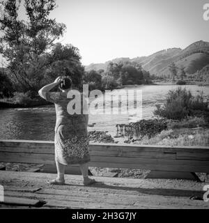 31. Juli, Russland, Altay, ländliche Szene mit einer Frau auf der Brücke, die horison auf dem Hintergrund der Berge betrachtet Stockfoto