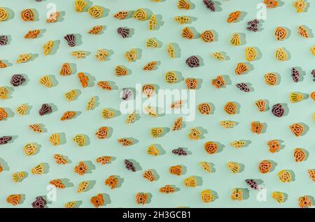 Ein helles Muster aus Pasta in Form von Halloween-Symbolen auf pastellgrünem Hintergrund. Halloween Essen oder Mahlzeit kreatives Konzept. Stockfoto
