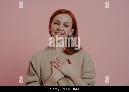 Eine friedvolle junge, rothaarige Frau, die ihre Hände auf der Brust hielt und dankte und ein Dankeszeichen zeigte Stockfoto
