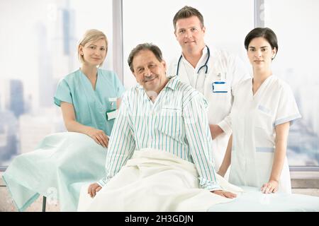 Älterer Patient im Bett mit Krankenhausteam Stockfoto
