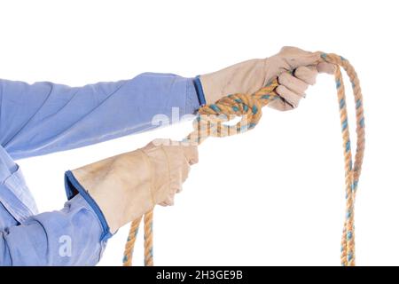 Zwei Hände binden einen einfachen Knoten an ein Seil, isoliert auf weißem Hintergrund. Hände mit Handschuhen, die einen acht Knoten mit einem Seil festziehen. Schutzhandschuhe. Stockfoto