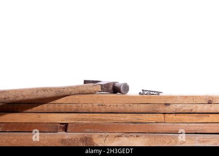 Hammer und Nägel auf Holzbrettern, isoliert auf weißem Hintergrund. Konzept der Zimmerei. Schreinerei-Werkzeuge. Stockfoto