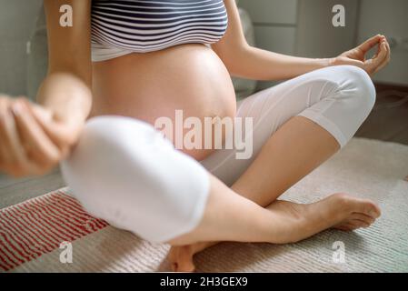 Nahaufnahme einer Schwangeren. Frau macht Meditation Stockfoto