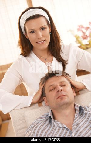 Attraktive Frau, die dem Mann Kopfmassage gibt Stockfoto