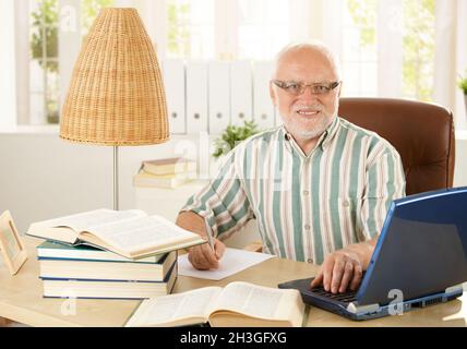 Porträt eines hohen Professors, der am Schreibtisch sitzt Stockfoto