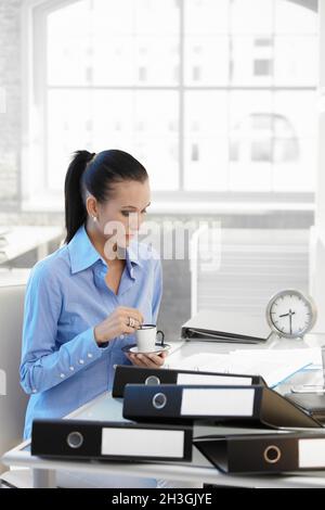 Vielbeschäftigte Geschäftsfrau, die Kaffee an der Rezeption getrunken hat Stockfoto