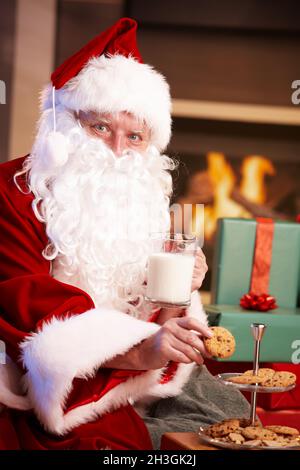 Weihnachtsmann mit Milch und Schokoladenkeksen Stockfoto