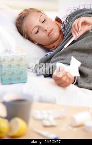 Junge Weibchen erkältet im Bett liegend Stockfoto