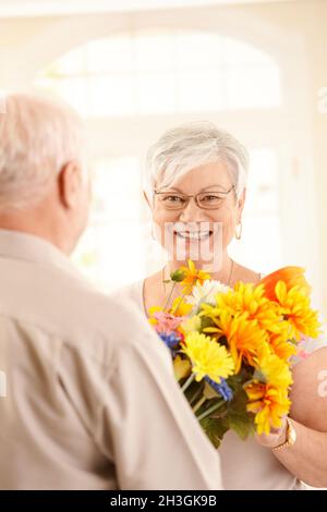 Lachende ältere Frau bekommt Blumenstrauß Stockfoto