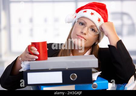 Junge Frau im weihnachtsmann hat im Büro erschöpft Stockfoto