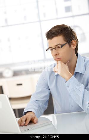 Junger Geschäftsmann, der sich auf Computerarbeit konzentriert Stockfoto