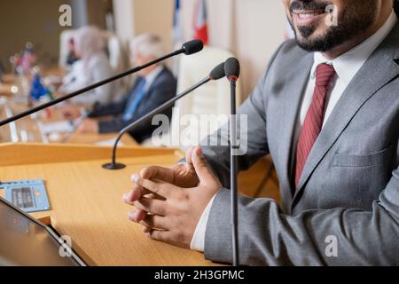 Nahaufnahme eines lächelnden männlichen Politikers mit zusammengeknallten Händen, die auf dem Platz stehen und Fragen der Öffentlichkeit beantworten Stockfoto