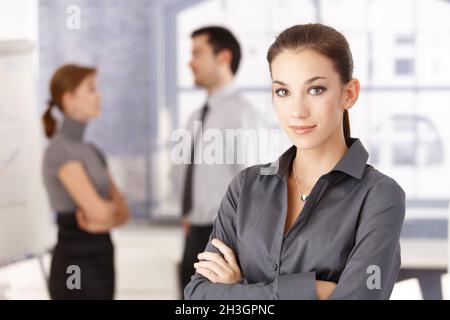 Junge Büroangestellte, die Arme gekreuzt stehen Stockfoto