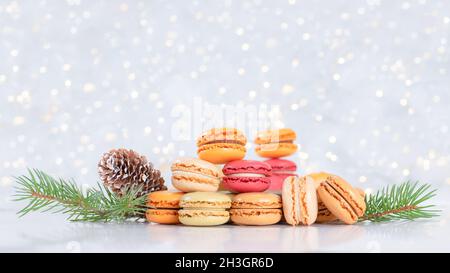 Bunte Macarons mit Kiefernästen auf weihnachtlich beleuchtetem Hintergrund. Hochwertige Fotos Stockfoto