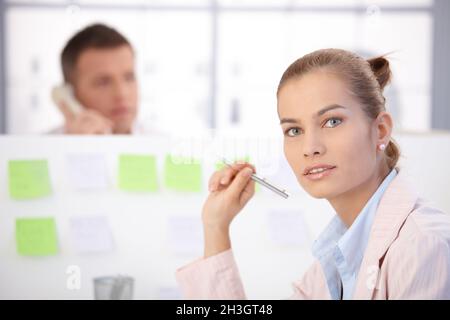 Hübsche Büroangestellte, die am Schreibtisch sitzt Stockfoto