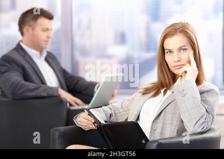 Attraktive Geschäftsfrau, die in der Bürolobby sitzt Stockfoto