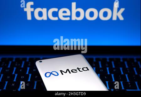 META Firmenlogo gesehen Smartphone, das auf Laptop-Tastatur mit Facebook-Logo auf dem Bildschirm platziert ist. Neues Facebook-Firmenlogo. Stafford, United Kin Stockfoto