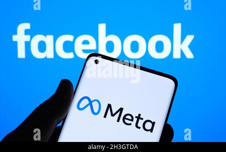 META-Firmenlogo auf dem Smartphone gesehen Halten Sie in der Hand und verschwommenes Facebook-Logo auf dem Hintergrundbildschirm. Neues Facebook-Firmenlogo für METAVERSE. Stafffor Stockfoto