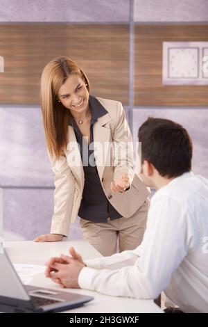 Junge Kollegen unterhalten sich lächelnd im Büro Stockfoto