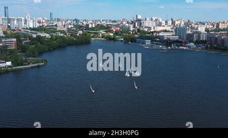 Luftaufnahme des Hafens mit weißen schönen Segelbooten im Stadtteich. Video. Kleine Yachten segeln in der Nähe der Seebrücke im Hintergrund von Jekaterinburg Stockfoto