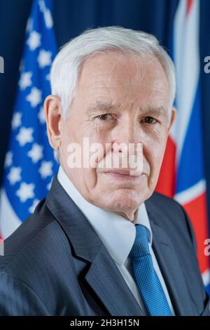 Porträt eines ernsthaften hochrangigen kaukasischen Kongressabgeordneten in einer formellen Klage gegen Nationalflaggen Stockfoto