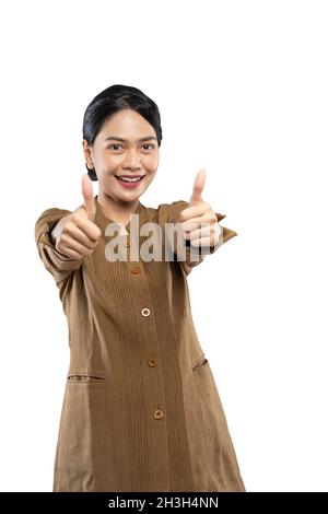 Selbstbewusste Zivilfrau in Uniform stehend mit zwei Daumen hoch zur Kamera Stockfoto