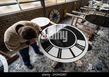 Regensburg, Deutschland. Oktober 2021. Ein Mitarbeiter des Turmuhrherstellers Rauscher arbeitet am Zifferblatt einer Turmuhr. Am Sonntag (31.10.2021) wird die Uhr von drei auf zwei Uhr Winterzeit zurückgestellt. Quelle: Armin Weigel/dpa/Alamy Live News Stockfoto