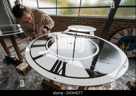 Regensburg, Deutschland. Oktober 2021. Ein Mitarbeiter des Turmuhrherstellers Rauscher arbeitet am Zifferblatt einer Turmuhr. Am Sonntag (31.10.2021) wird die Uhr von drei auf zwei Uhr Winterzeit zurückgestellt. Quelle: Armin Weigel/dpa/Alamy Live News Stockfoto