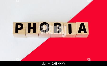 Holzblöcke mit dem Text: Phobie auf weißem und rotem Hintergrund Stockfoto