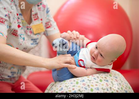 Der Arzt macht mit einem Neugeborenen Übungen. Stockfoto