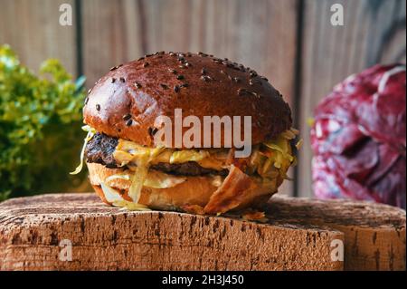 Nahaufnahme von Rindfleisch-Burger auf Schneidebrett mit Salat im Hintergrund Stockfoto