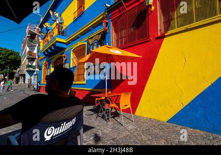Ein Mann entspannt sich neben den hell gestrichenen Wänden in La Boca, Buenos Aires, Argentinien Stockfoto