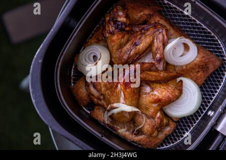 Gebackene eingelegte Hähnchenflügel und Zwiebeln. Beim Kochen von Hähnchen mit Gewürzen wird eine Brotscheibe im Heißluftofen eingelegt. Selektiver Fokus. Stockfoto