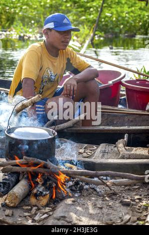 Amazonas, PERU - 28 Dez.: Unbekannter amazonischen indigenen Mann Kochen Fisch über eine hölzerne Floß am 28. Dezember 2009, im Innenmin Stockfoto