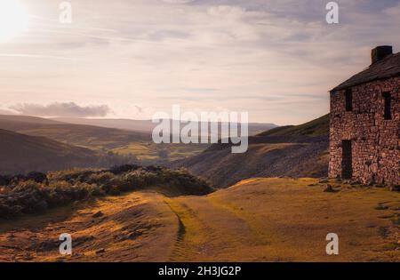 Verlassene ehemalige Beldi Hill Bleibergwerk auf einem Hügel über Crackpot Hall bei Sonnenuntergang, Swaledale, North Yorkshire, England Stockfoto